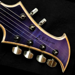 Ichor headstock featuring a stunning purple ombre finish on beautifully figured maple, paired with Gotoh tuners. A striking blend of natural wood character and bold, shifting colors.